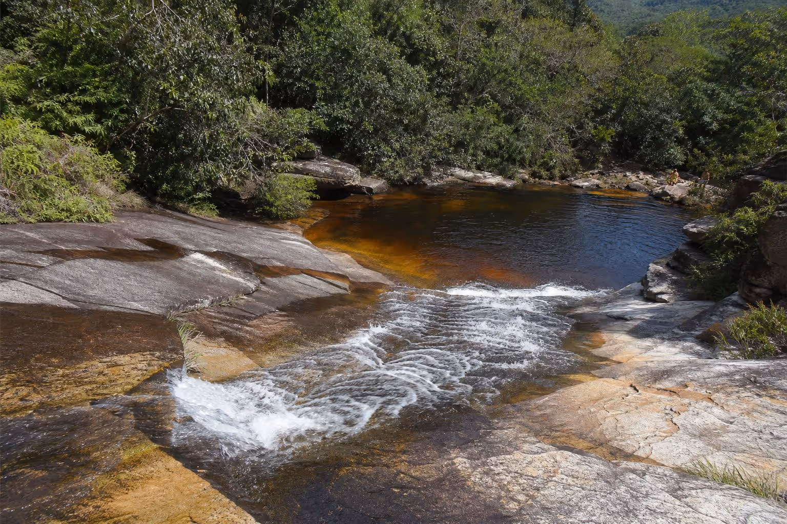 Pessoa escorregando pela pedra natural do Ribeirão do Meio até o poço, perto de Lençóis