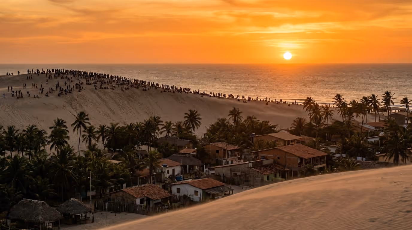 Duna de areia branca com pessoas observando o pôr do sol em Jericoacoara, Ceará